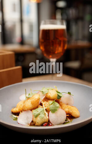 Fish tempura on grey porcelain plate with glass of beer in blurred background Stock Photo