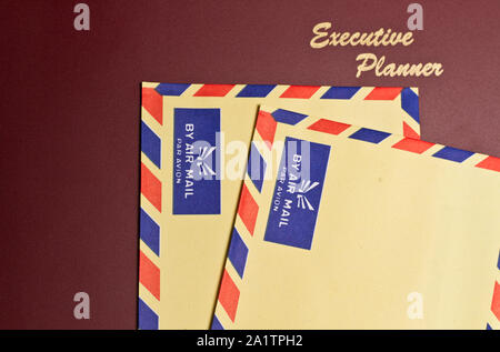 a dark red executive planner with two yellow color envelopes Stock Photo