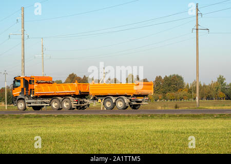 Orange dump truck goes on country highway Stock Photo