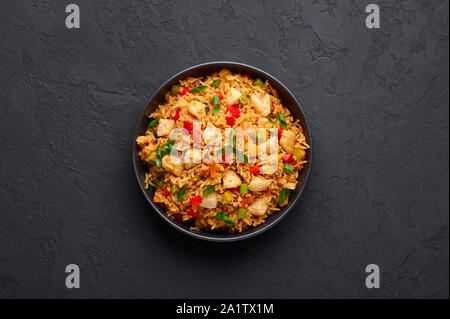 Schezwan Chicken Fried Rice in black bowl at dark slate background. Szechuan Rice is indo-chinese cuisine dish with bell peppers, green beans, carrot, Stock Photo