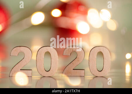 The inscription 2020, New Year and Christmas, from behind blurred dots of light on a blue background and red balls on the Christmas tree. Christmas an Stock Photo