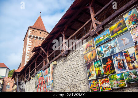 Outdoor paintings gallery selling and hanging on the old wall of St. Florian's Gate, a famous tourists attraction in Krakow, Poland Stock Photo