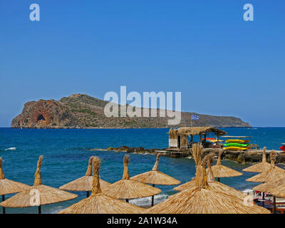 Thatched umbrellas along the beach with a water sports hut in the background at Agia Marina beach, Chania, Crete, Greece. Stock Photo