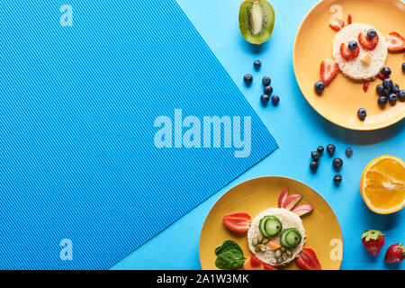 top view of plates with fancy animals made of food on blue background Stock Photo