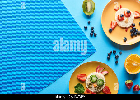 top view of plates with fancy animals made of food on blue background Stock Photo