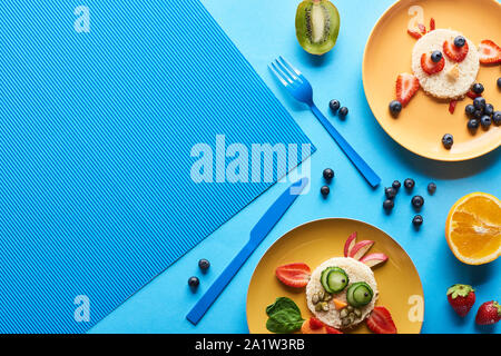 top view of plates with fancy animals made of food on blue background Stock Photo