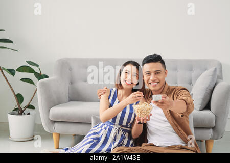 Excited couple watching tv together sitting on a sofa in the living room at home Stock Photo