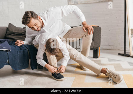 father teaching son to tying shoelaces at home Stock Photo