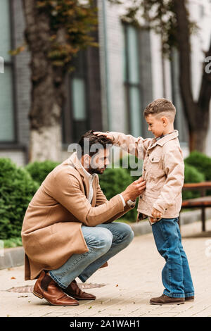 side view of dad in coat and son in jacket on street in autumn day Stock Photo