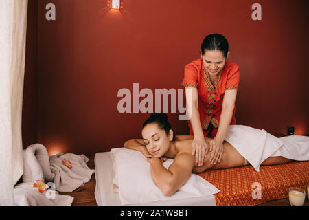 asian masseur doing back massage to woman on massage mat Stock Photo