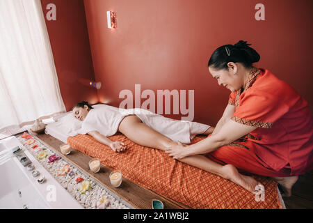 asian masseur doing foot massage to woman in spa salon Stock Photo