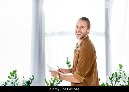 handsome and smiling man in shirt doing paperwork in office Stock Photo