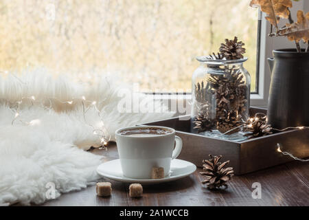 Fall cozy still life on windowsill at home interior. Cup of coffee at home warm fluffy furskin. Hygge concept. Creativity and inspiration. Stock Photo