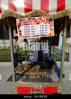 Istanbul,Turkey, March 08,2019:Street vendor selling roasted chestnuts  in tradition street food cart,close up on sunny day,in front of Hagia Sophia Stock Photo
