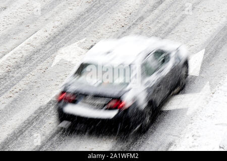 Blurry driving car on the empty city street with direction arrow street markings during a snowfall Stock Photo