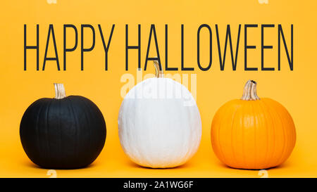 Three large Halloween pumpkins side by side over orange background. Halloween greeting card. Stock Photo