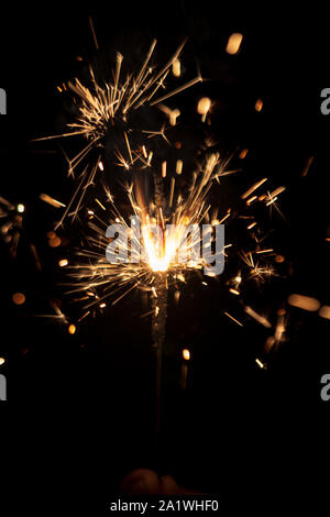 Sparkler- A person holding a burning sparkler isolated on black background. Holiday background image for diwali, christmas, new year, birthday celebra Stock Photo