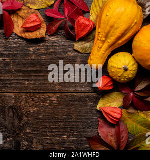 Happy Thanksgiving. Pumpkin and fallen leaves on dark wooden background. Autumn vegetables and seasonal decorations. Autumn Harvest and Holiday still Stock Photo