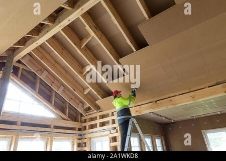 Construction worker thermally insulating eco wooden frame house Stock Photo