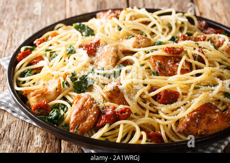 Pasta with dried tomatoes, chicken, parmesan and spinach close-up on a plate on the table. horizontal Stock Photo