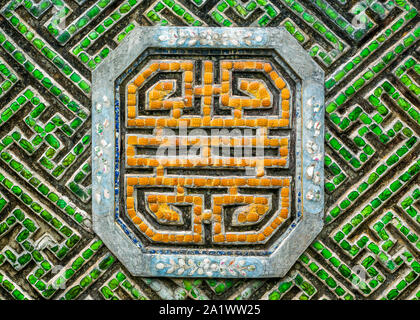 Traditional colorful mosaic ornament with Buddhist symbols made from precious stones in vibrant orange and green Stock Photo