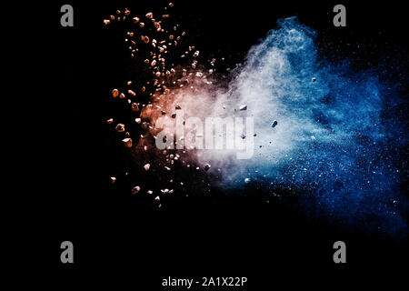Split debris of stone exploding with blue red powder against black background. Stock Photo
