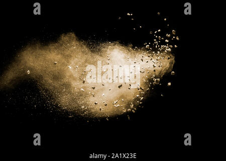 Split debris of brown stone exploding with brown powder against black background. Stock Photo