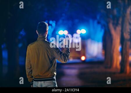 Young man looking at leaving ambulance car of emergency medical service. Concepts health care, rescue and goodbye. Stock Photo