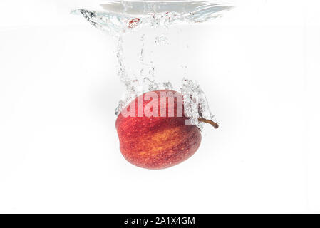 Apple falls under water with a splash. Stock Photo