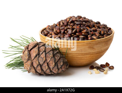 unpeeled cedar nuts in bowl and branch with pine cone isolated on white background Stock Photo