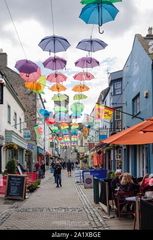 Art installation colourful display of umbrellas hanging above a narrow old street with pavement cafes. Palace Street, Caernarfon, Gwynedd, Wales, UK Stock Photo