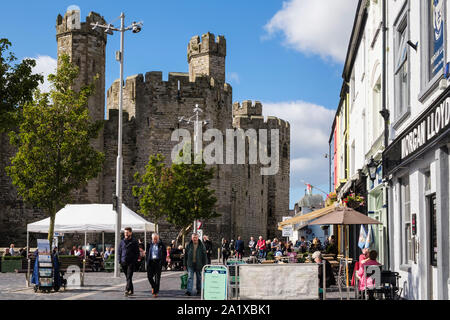 Street scene with people dining outside in pavement cafes in busy historic Castle Square, Caernarfon, Gwynedd, Wales, UK, Britain Stock Photo