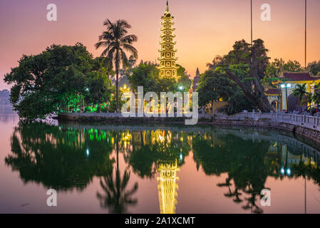 Hanoi buddhist pagoda on West Lake, colorful sunset, illuminated temple, water reflection. Chua Tran Quoc on Ho Tay at Hanoi, Vietnam travel. Stock Photo