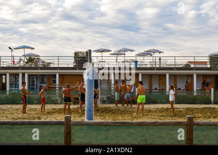 A coach teaches beach volleyball to a group of boys on the sandy beach of a bathing establishment in summer, Lido di Camaiore, Tuscany, Versilia,Italy Stock Photo