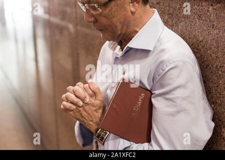 Aparecida, São Paulo, Brazil - January 13, 2016: Faithful man prays at Cathedral of Nossa Senhora  Aparecida National Sanctuary with bible under arm Stock Photo