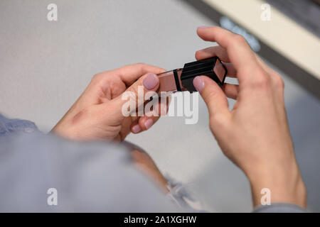 woman customer is testing lipstick by putting it on her arm in make-up shop. Stock Photo
