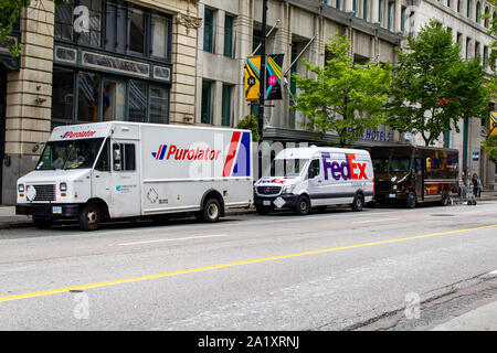 Purolator, FedEx and UPS trucks parked on the street Stock Photo
