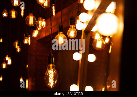 classic different retro light bulbs hanging on brick wall background at night. Stock Photo