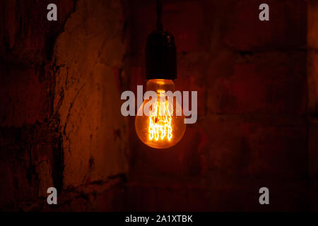 classic different retro light bulbs hanging on brick wall background at night. Stock Photo