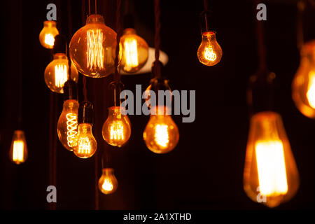 classic different retro light bulbs hanging on brick wall background at night. Stock Photo