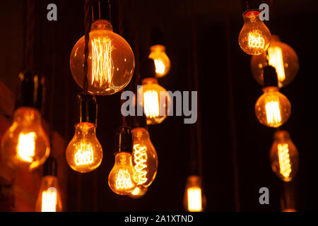 classic different retro light bulbs hanging on brick wall background at night. Stock Photo