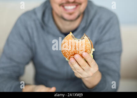 Smiling man hold fresh burger in hand background Stock Photo