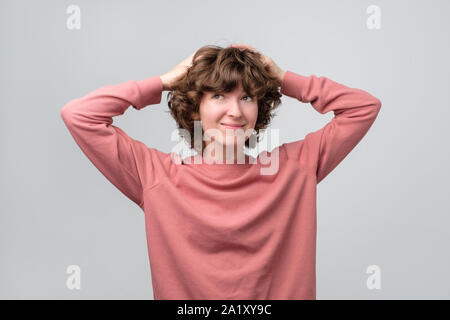 Smiling curly thinking woman looking up dreaming or planning something. Studio shot Stock Photo