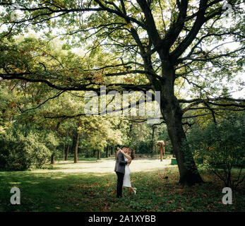 Portrait of kissing couple in the garden under huge oak Stock Photo