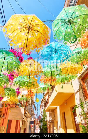 Street decorated with umbrellas of different colours in Aegina town on summer sunny day, Aegina island, Greece Stock Photo