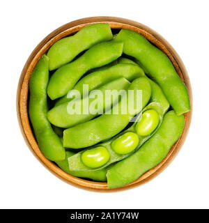 Green soybeans in the pod, edamame, in wooden bowl. Unripe soya beans, also Maodou. Glycine max, a legume, edible after cooking. Protein source. Stock Photo