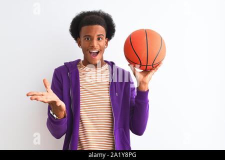 Young african american sportsman holding basketball ball over isolated white background very happy and excited, winner expression celebrating victory Stock Photo