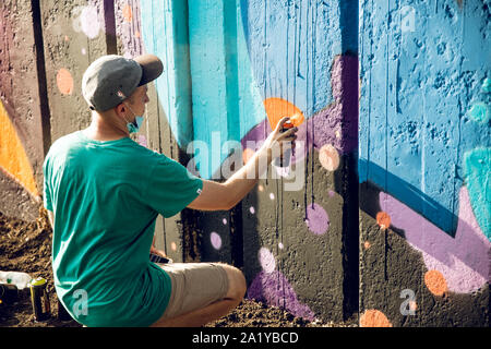 KKARKIV, UKRAINE JULY 30, 2019: A fellow draws bright street graffiti. Stock Photo