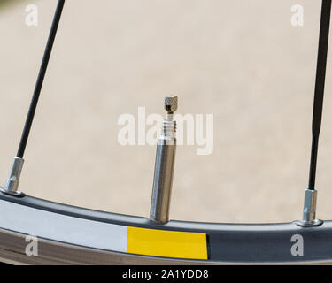 Closeup of bicycle tire valve stem, presta style, in the open position on a road bike wheel Stock Photo
