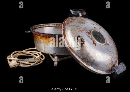 Old aluminum electric cookware. Kitchen accessories used in Central Europe. Dark background. Stock Photo